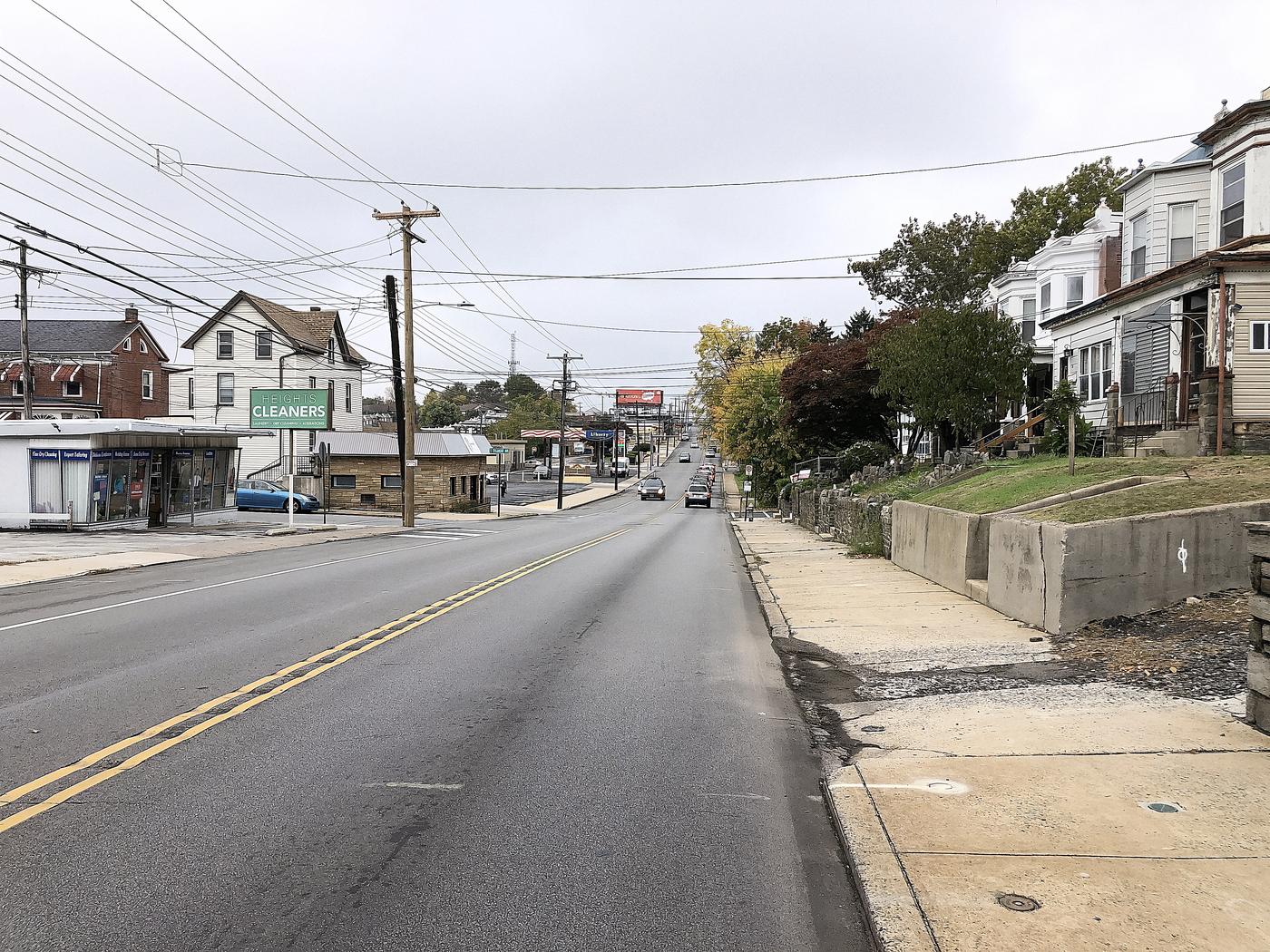 Baltimore Avenue in Clifton Heights, looking south-west from Springfield Road. Storefronts at the pavement, rows going up the hill behind them.