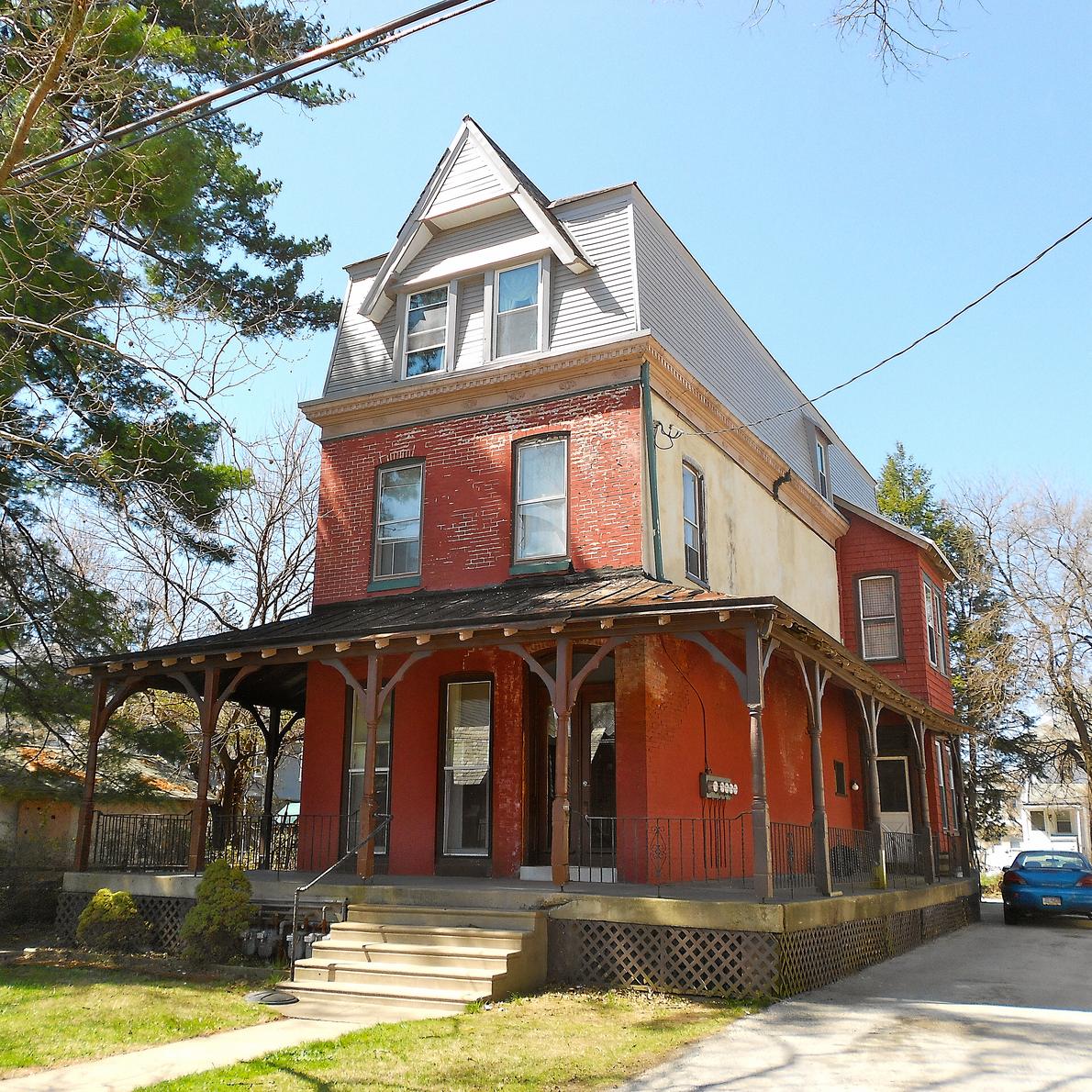 A house in East Lansdowne, brick with a porch running the width of it.