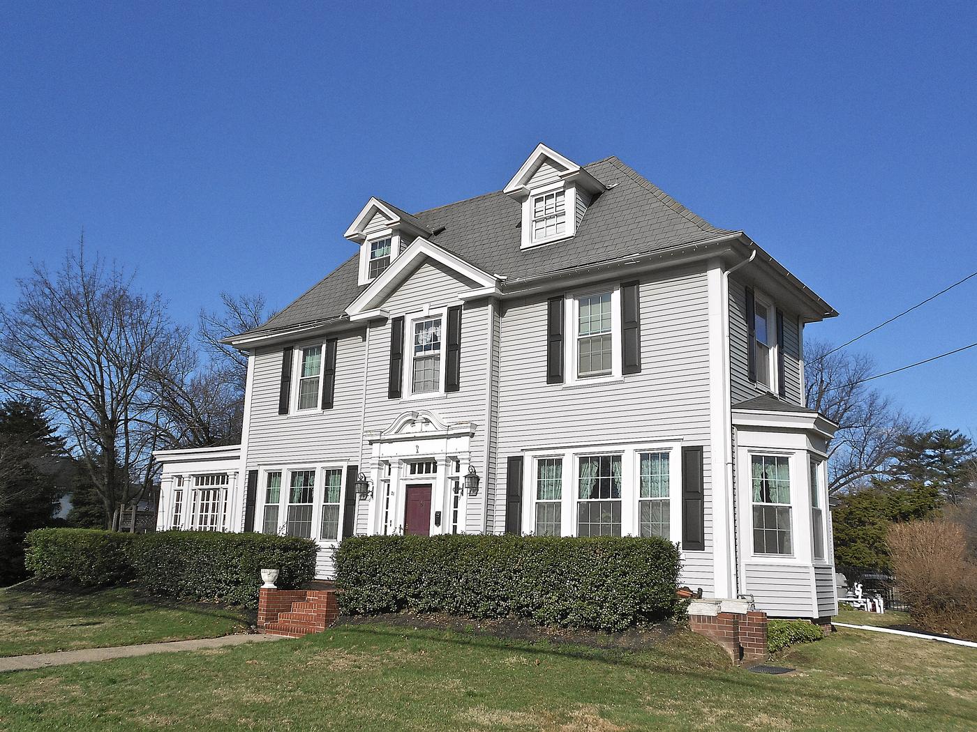 A house in Ridley Park. White clapboard, dormers, a porch across the whole front, and a lot with room on both sides.